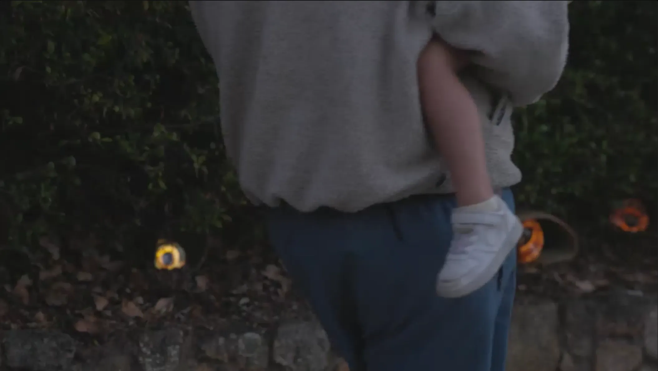 A photo of a man walking, holding a child.